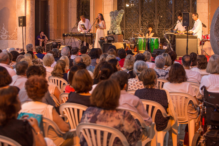 Cumie singing to a seated audience in the courtyard of the Palau March, Palma.